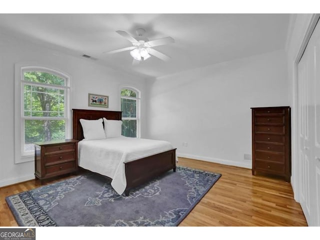 bedroom featuring a closet, multiple windows, wood finished floors, and baseboards