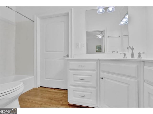 full bath with toilet, vanity, wood finished floors, and shower / bathtub combination