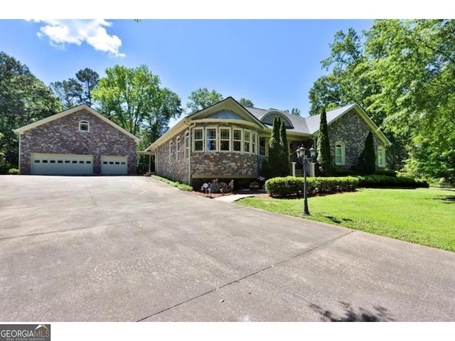 view of front of home with driveway, stone siding, and a front yard