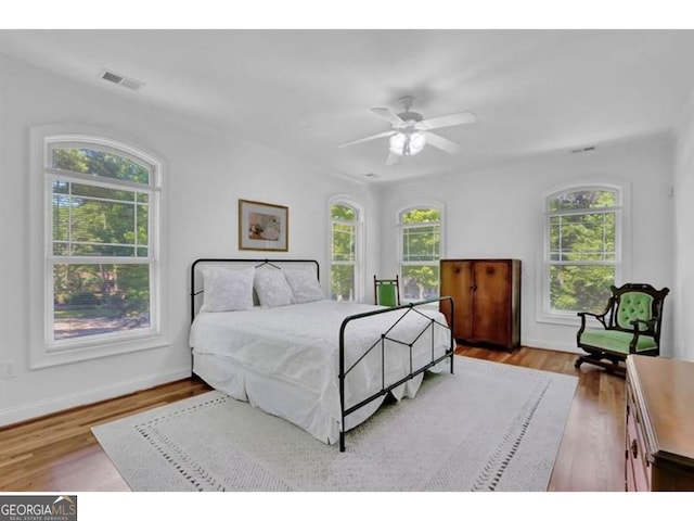 bedroom with light wood-style floors, baseboards, visible vents, and a ceiling fan