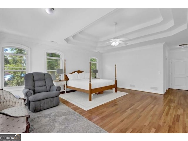 bedroom featuring ceiling fan, a tray ceiling, and wood finished floors