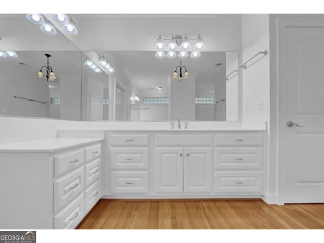 full bath featuring a chandelier, double vanity, a sink, and wood finished floors