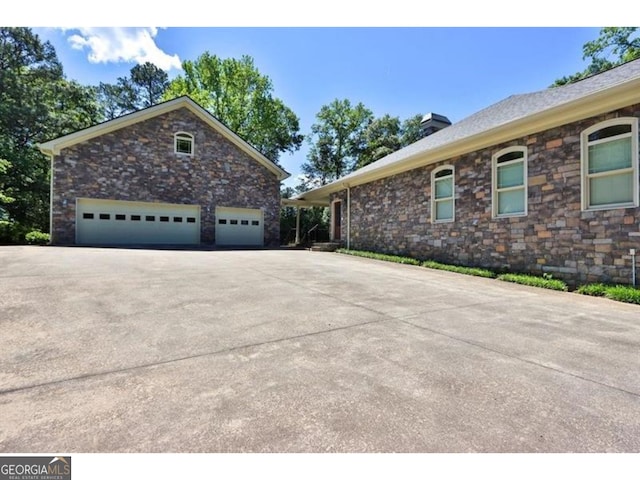 view of side of home with driveway and a chimney