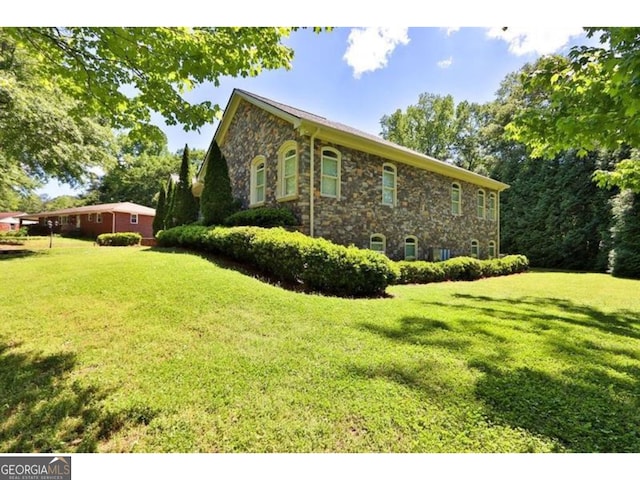 view of property exterior with stone siding and a lawn