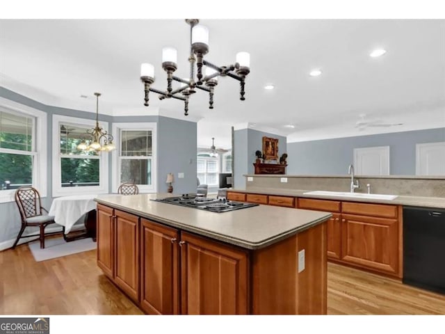 kitchen featuring brown cabinets, decorative light fixtures, light countertops, a sink, and black appliances