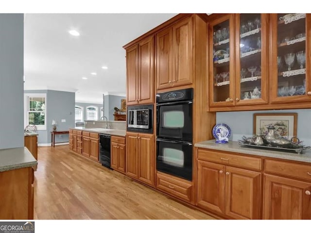 kitchen featuring dobule oven black, beverage cooler, light countertops, brown cabinets, and glass insert cabinets