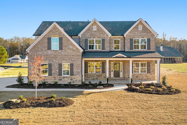 view of front of home featuring a porch, a front yard, brick siding, and roof with shingles