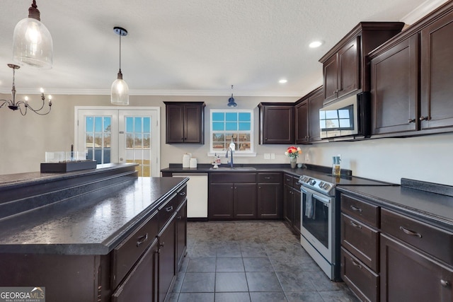 kitchen featuring stainless steel appliances, dark countertops, a sink, and decorative light fixtures