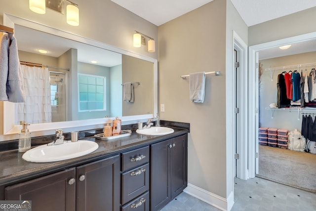 full bath featuring double vanity, a sink, a walk in closet, and a shower stall