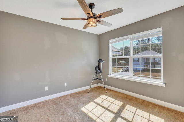 empty room with baseboards, a ceiling fan, and light colored carpet