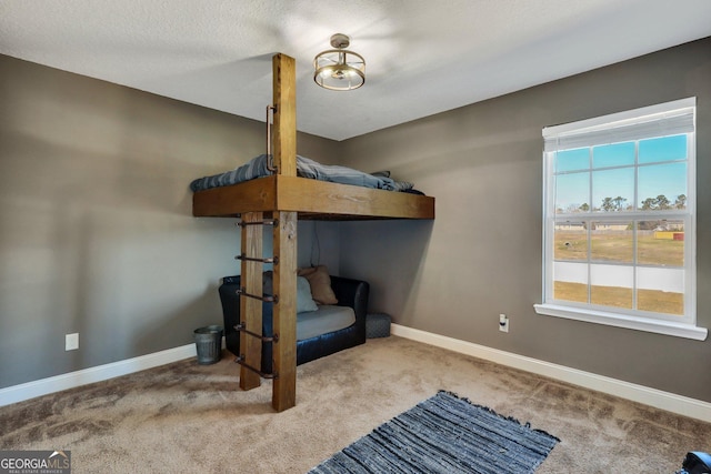 bedroom with light colored carpet, a textured ceiling, and baseboards