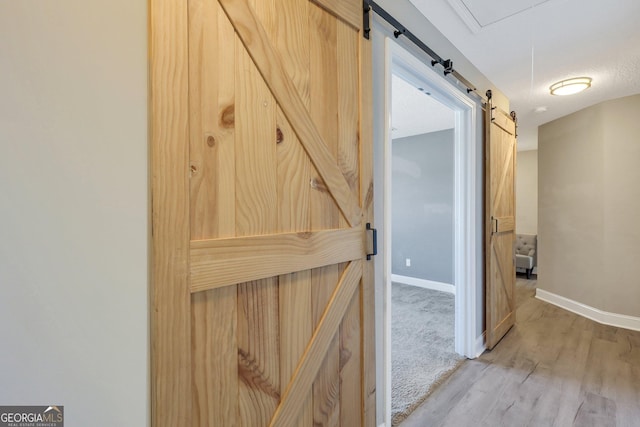 interior space featuring light wood finished floors, a barn door, baseboards, and a textured ceiling