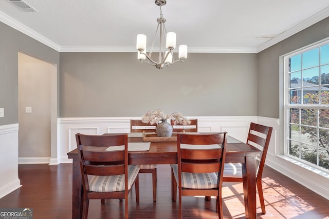 dining room with dark wood-style floors, a wainscoted wall, visible vents, ornamental molding, and a chandelier