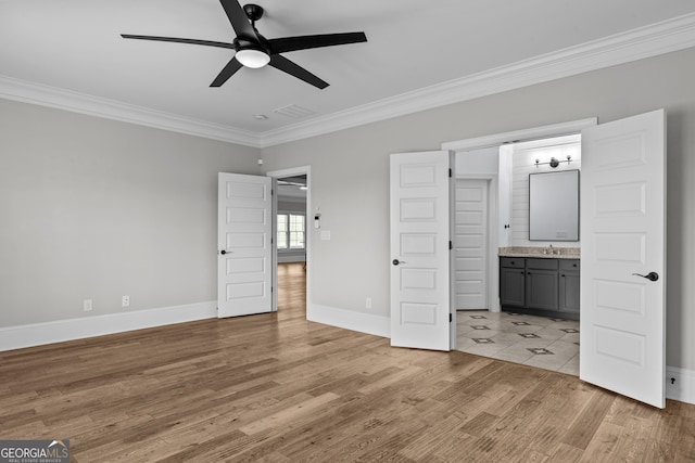 unfurnished bedroom featuring ensuite bathroom, baseboards, wood finished floors, and crown molding