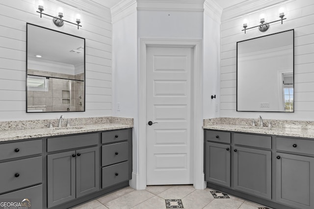 bathroom featuring ornamental molding, a stall shower, two vanities, and a sink