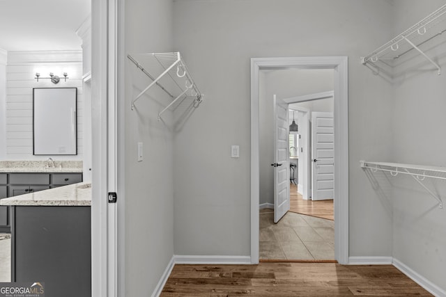 walk in closet with a sink and wood finished floors