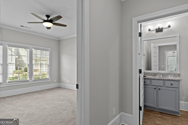 interior space with ornamental molding, visible vents, a sink, and baseboards