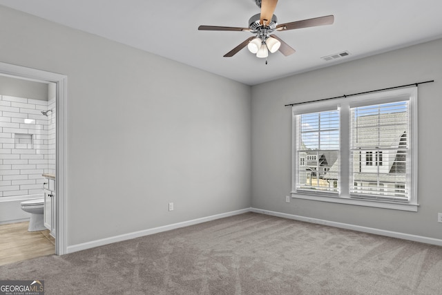 unfurnished bedroom featuring visible vents, baseboards, a ceiling fan, connected bathroom, and carpet