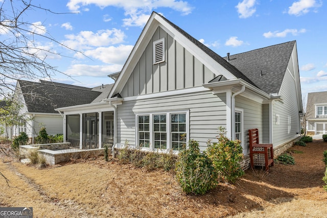 back of house with a sunroom, a shingled roof, and board and batten siding