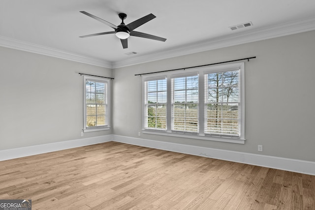 empty room featuring light wood-style flooring, visible vents, ornamental molding, and baseboards