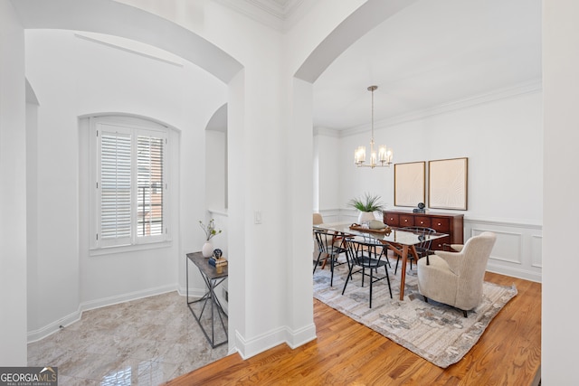 dining area featuring light wood-style floors, a chandelier, and crown molding