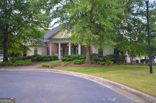 greek revival house with brick siding and a front yard