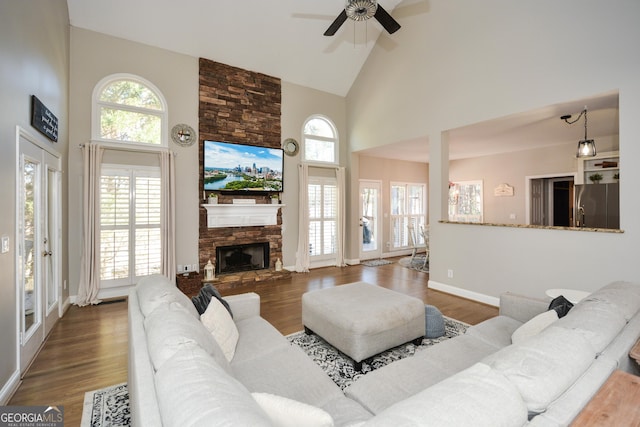 living room with dark wood-style floors, baseboards, a fireplace, and high vaulted ceiling