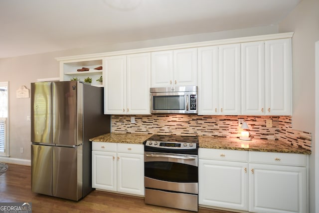 kitchen with appliances with stainless steel finishes, dark stone countertops, white cabinetry, and decorative backsplash