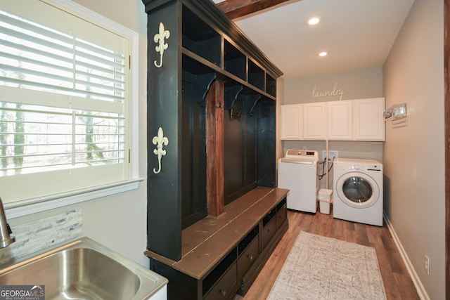 clothes washing area featuring recessed lighting, cabinet space, wood finished floors, washer and dryer, and baseboards