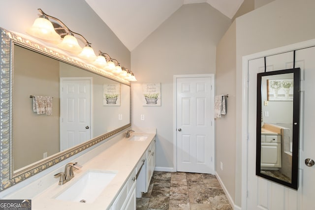 bathroom with lofted ceiling, double vanity, baseboards, and a sink