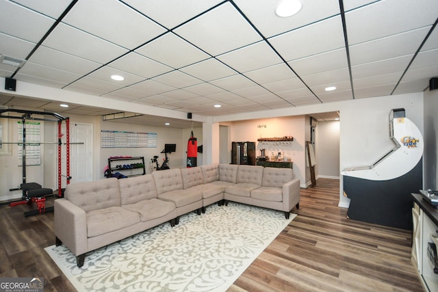 living room with baseboards, wood finished floors, a paneled ceiling, and recessed lighting