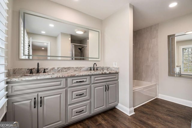 bathroom with double vanity, wood finished floors, a sink, and baseboards