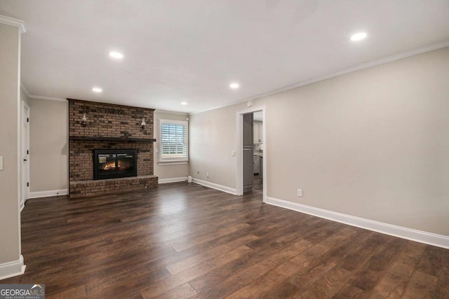 unfurnished living room with baseboards, ornamental molding, dark wood-style flooring, a brick fireplace, and recessed lighting