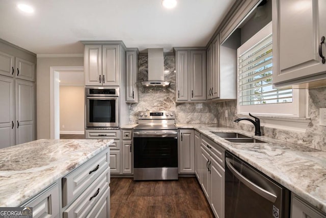 kitchen featuring wall chimney exhaust hood, light stone counters, stainless steel appliances, gray cabinetry, and a sink