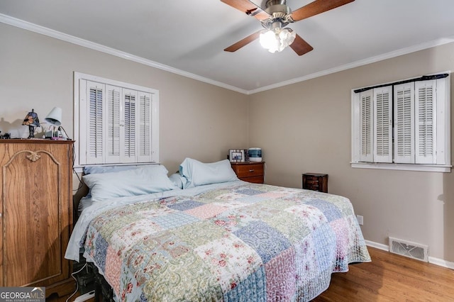 bedroom featuring wood finished floors, visible vents, and crown molding