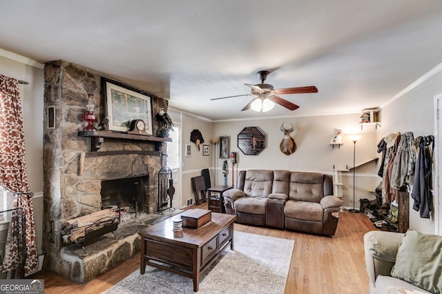 living area featuring a stone fireplace, light wood-type flooring, and crown molding