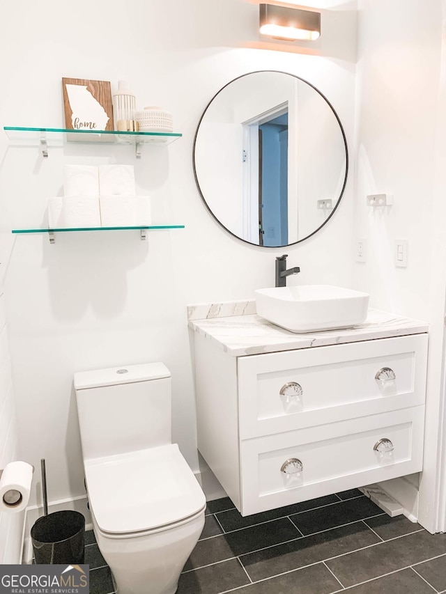 half bath with toilet, vanity, and tile patterned floors