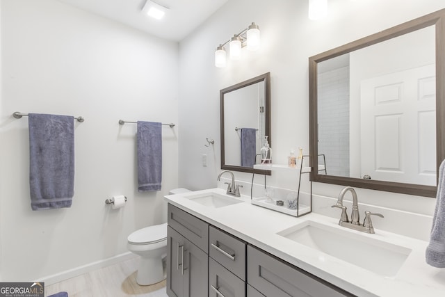 full bathroom with baseboards, a sink, toilet, and double vanity