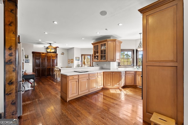 kitchen with a barn door, glass insert cabinets, a peninsula, light countertops, and pendant lighting