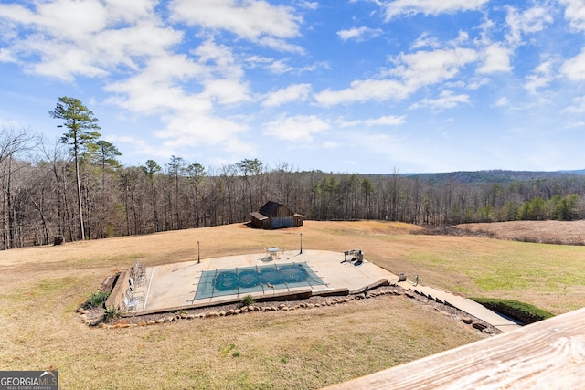 exterior space featuring a lawn, a wooded view, and a covered pool