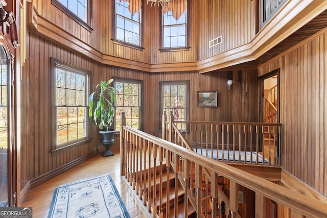 corridor featuring a wealth of natural light, wood walls, and an upstairs landing