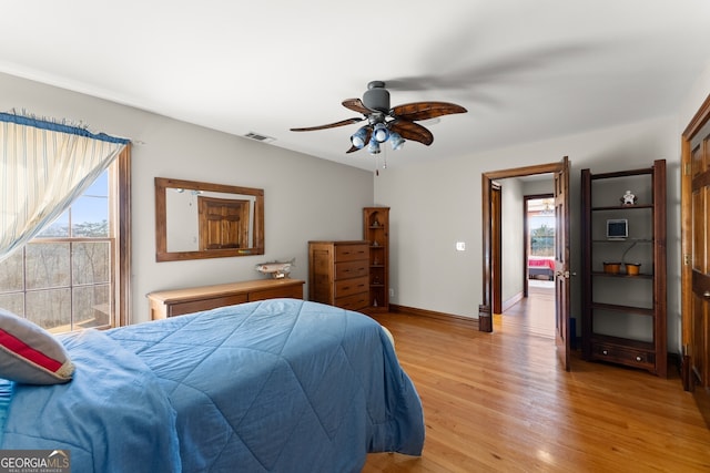 bedroom featuring light wood finished floors, visible vents, baseboards, and ceiling fan