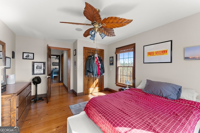 bedroom with light wood-type flooring, a closet, ceiling fan, and baseboards