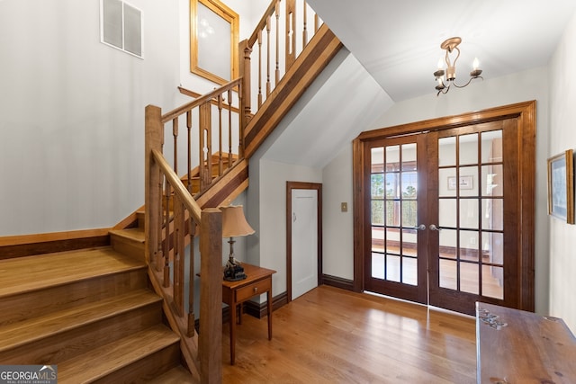 interior space with french doors, visible vents, wood finished floors, a chandelier, and stairs