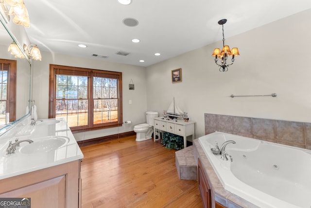 full bathroom with visible vents, toilet, a sink, wood finished floors, and a tub with jets