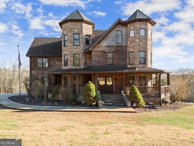 view of front of property with a porch, stone siding, and a front lawn