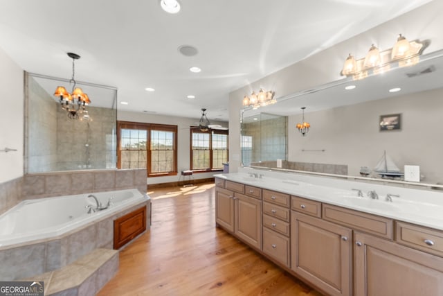 bathroom with double vanity, wood finished floors, a sink, and a notable chandelier