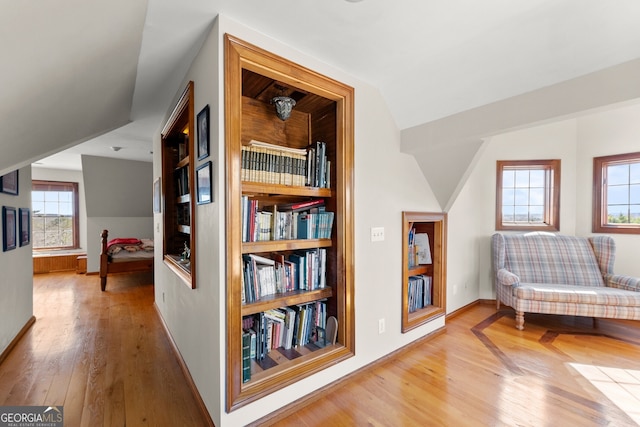 sitting room featuring light wood-type flooring, lofted ceiling, and baseboards