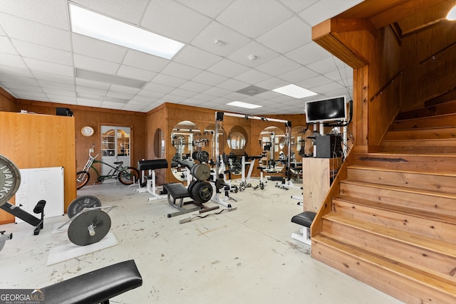 exercise area featuring a drop ceiling and wood walls