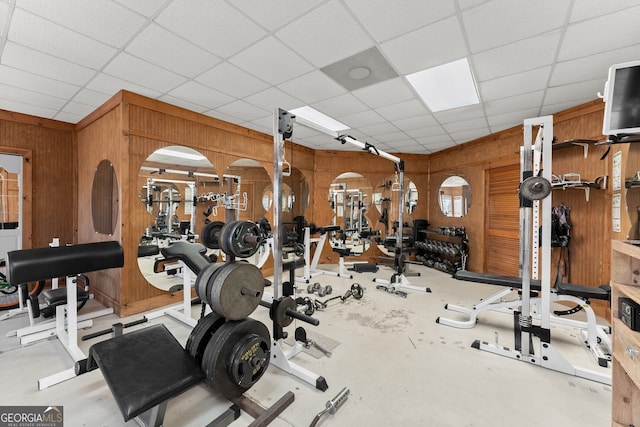 exercise room with a paneled ceiling and wooden walls